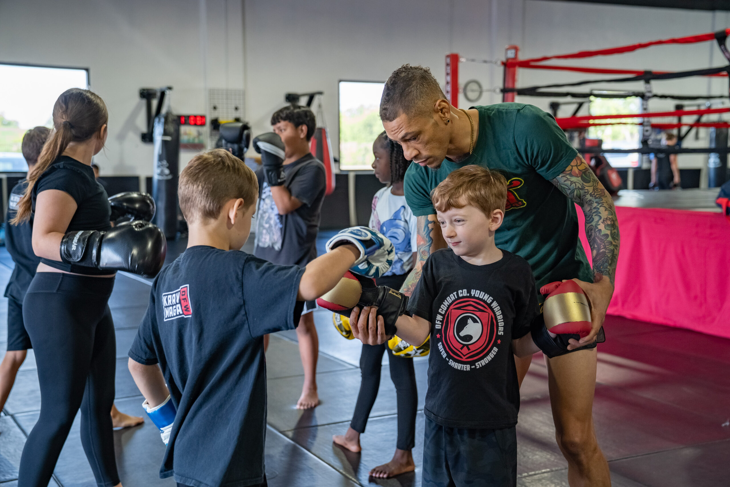 Instructor coaching two Young Warriors students during partner pad work
