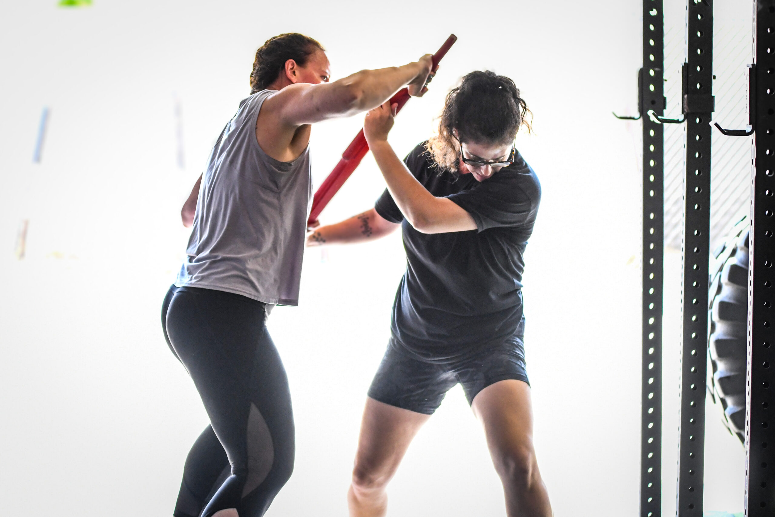 Two participants practicing a partner drill with padded training equipment